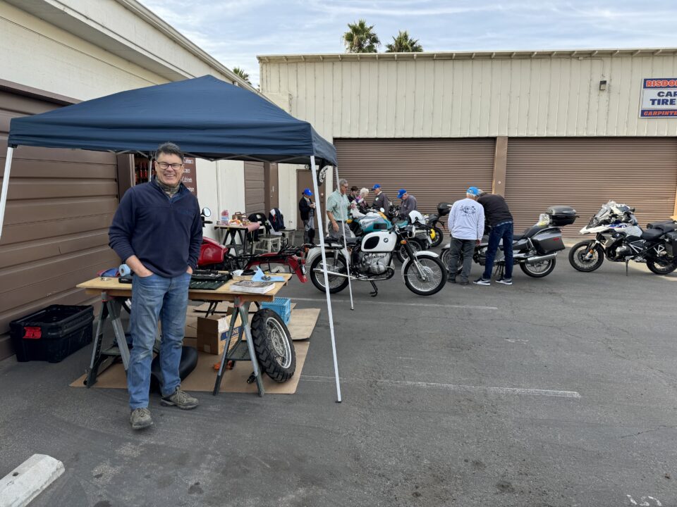 A man standing in front of a tent with motorcycles at Marten's Spring Tech Day.